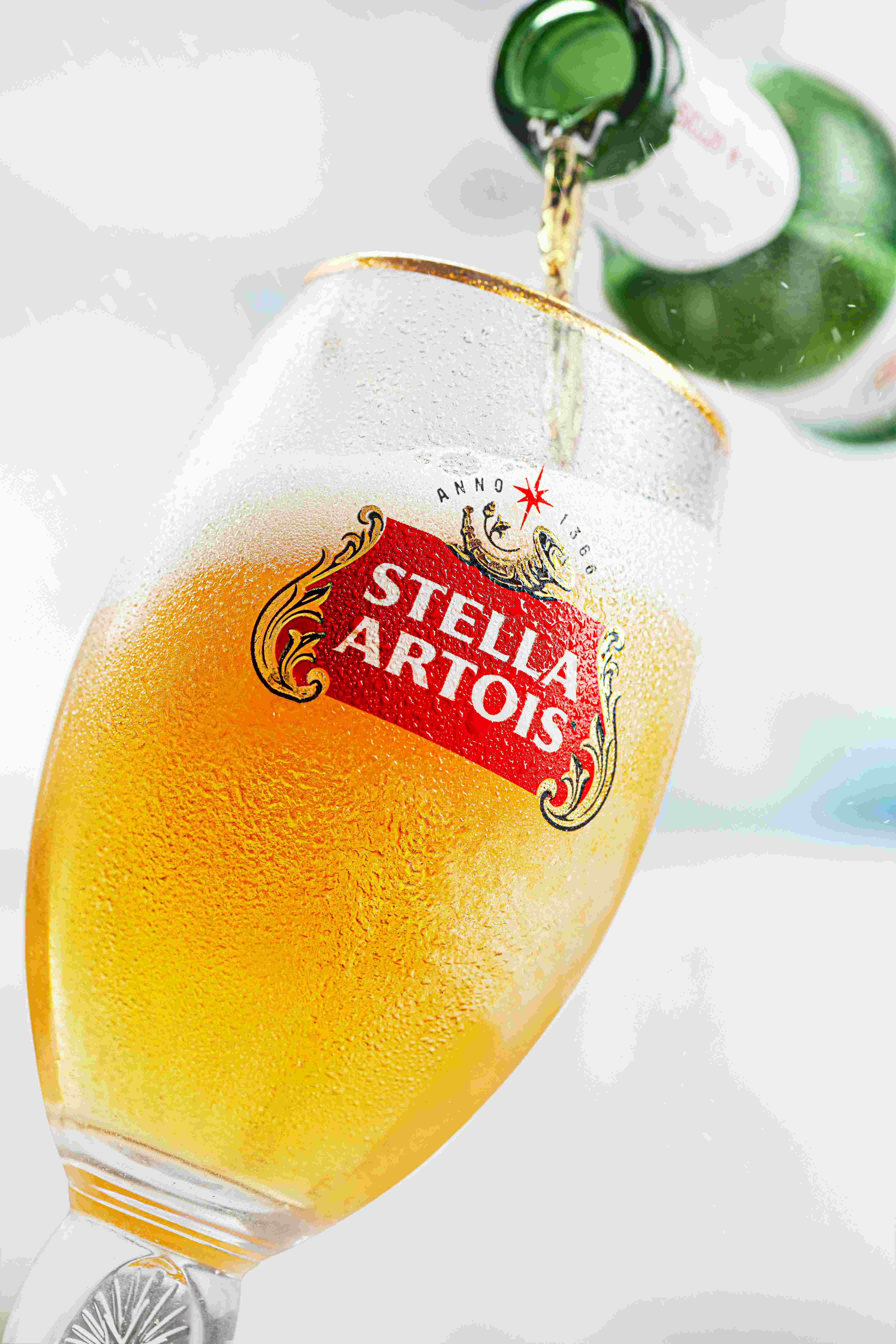 Stella Artois being poured from bottle into a pint glass